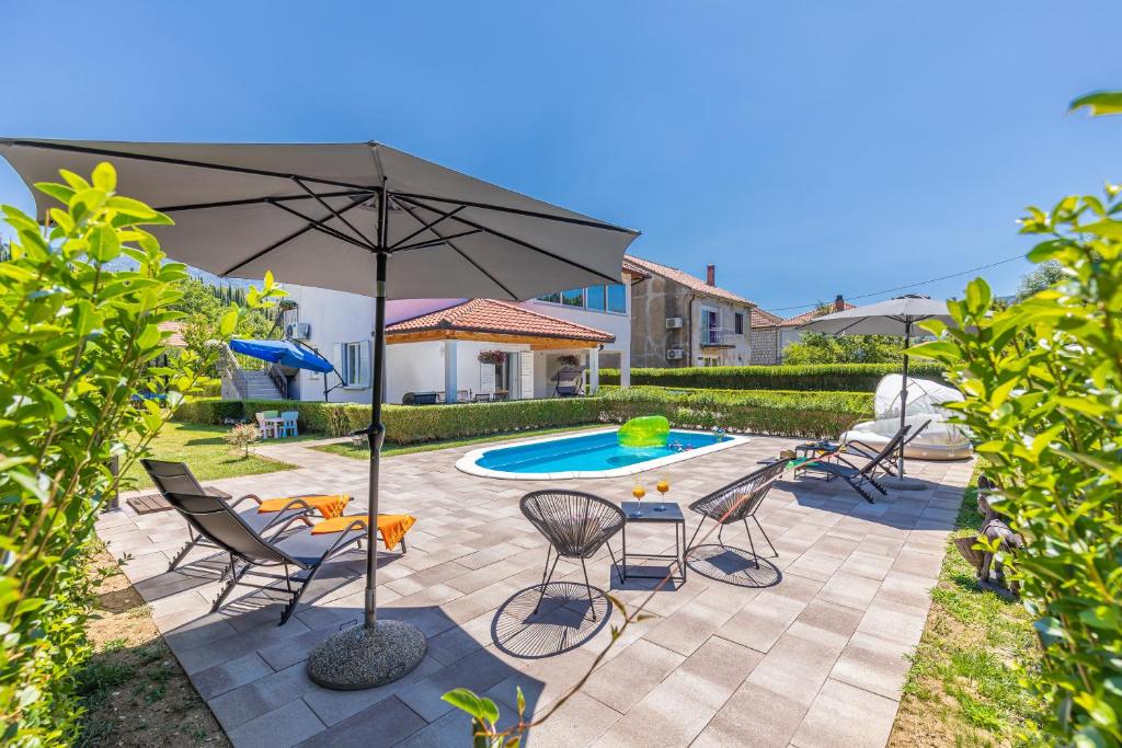 un patio con sillas, una sombrilla y una piscina en Green paradise with swimming pool en Gruda