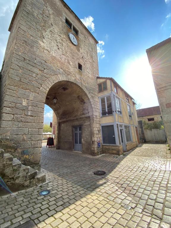 duży ceglany budynek z wieżą zegarową w obiekcie Logement entier - L'Appart des anges 1 w mieście Noyers-sur-Serein
