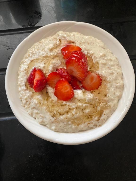 a white bowl of oatmeal with strawberries on top at Oakfield in Kenmare