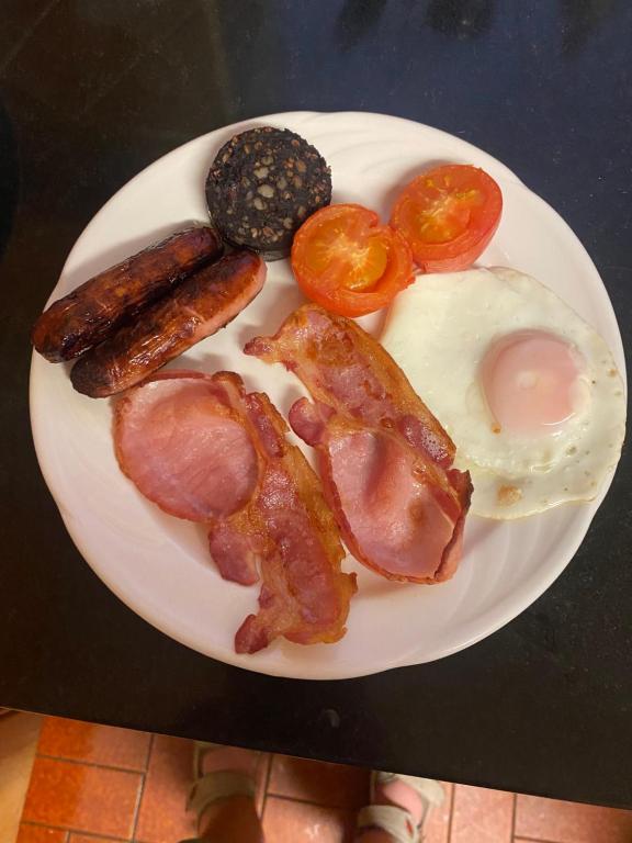 a plate of breakfast food with bacon eggs sausage and tomatoes at Oakfield in Kenmare