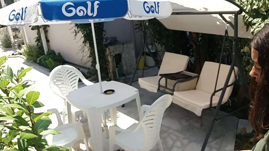 a woman standing next to a table and chairs under an umbrella at Apartment’s Maric - Zelenika,Herceg Novi in Zelenika