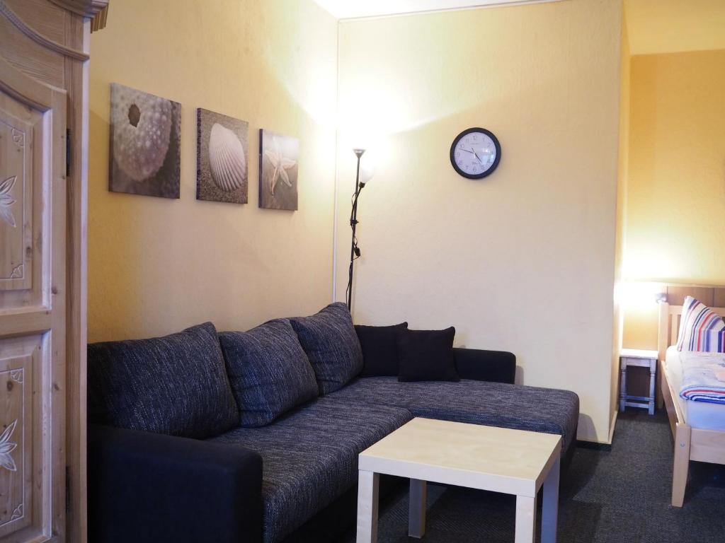 a living room with a couch and a clock on the wall at Friesenmeer Apartment in Bensersiel
