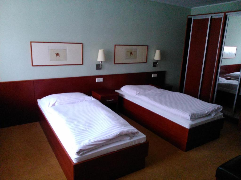 two beds in a room with a mirror at Hostel Refleks in Toruń