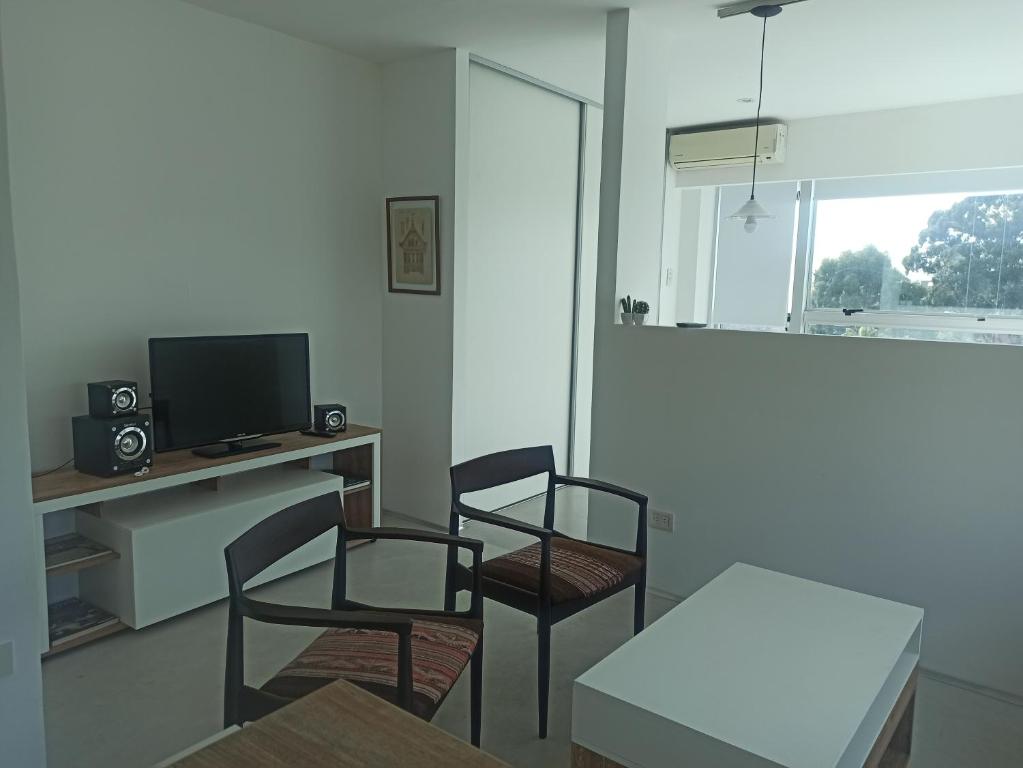 sala de estar con 2 sillas, mesa y TV en Ombu Loft Olivos, Vista al Rio in 