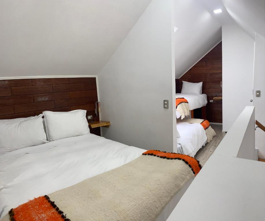 a bedroom with two beds with white sheets and an orange rug at loft puerto varas in Puerto Varas