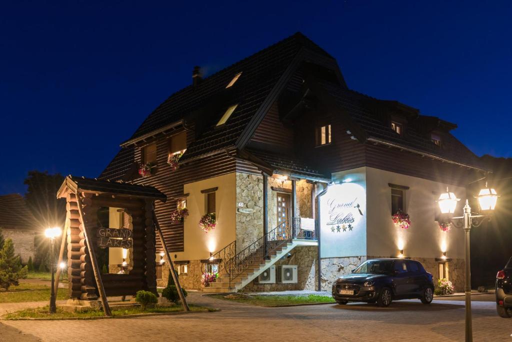 a house with a car parked in front of it at Grand Lakes Rooms in Plitvička Jezera