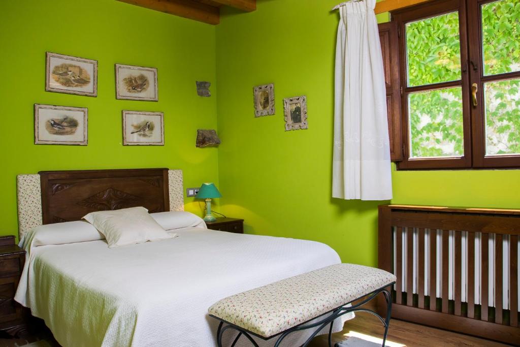 Dormitorio verde con cama y ventana en Casa Azulete, en Bimenes