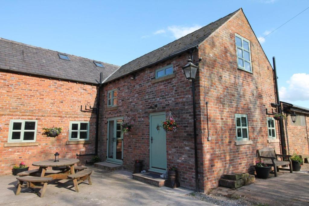 a brick building with a picnic table in front of it at The Hoglets in Goostrey