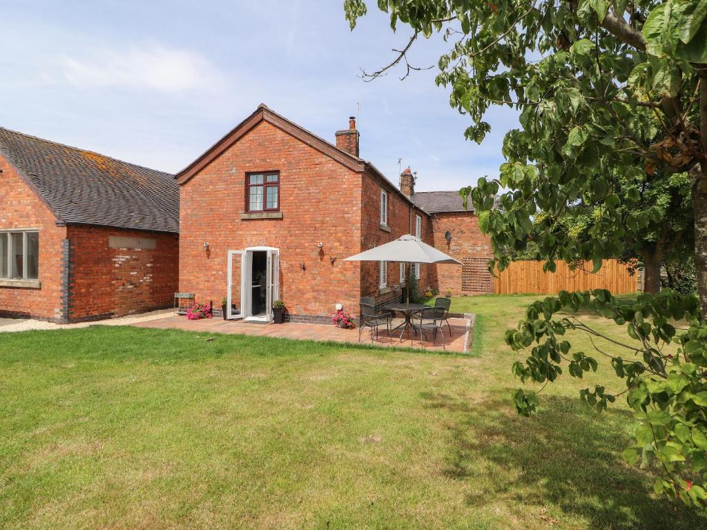 an external view of a brick house with an umbrella at Hill Farm in Nantwich