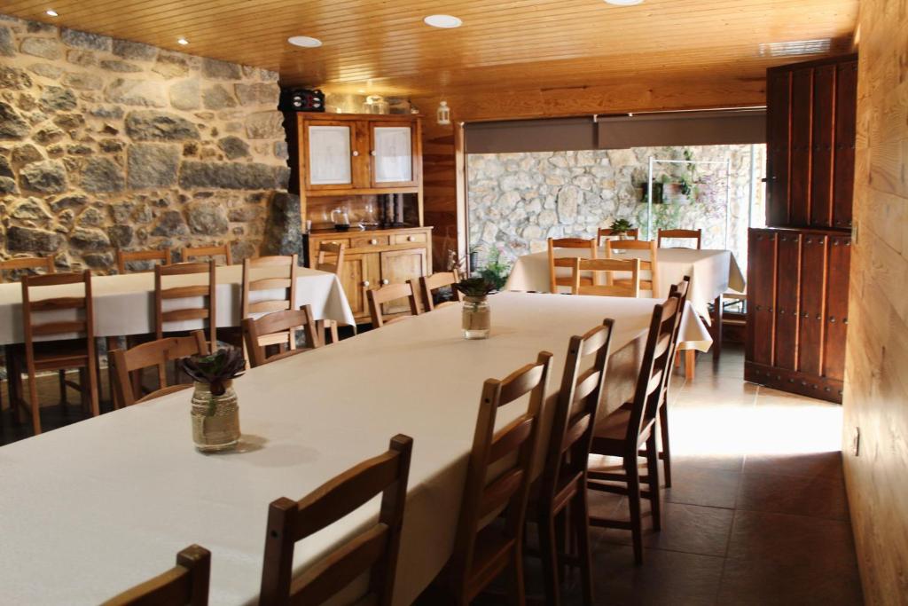 un comedor con mesas blancas y sillas de madera en Albergue Alto da Pena EXCLUSIVE FOR PILGRIMS, en Negreira