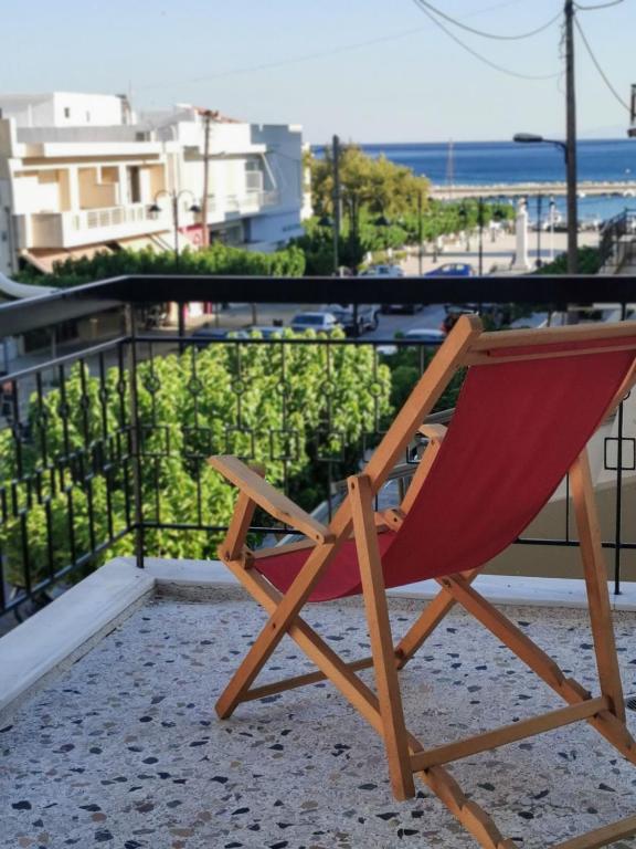 a wooden chair sitting on a balcony with a view of the ocean at Downtown Apartment Karystos in Karistos