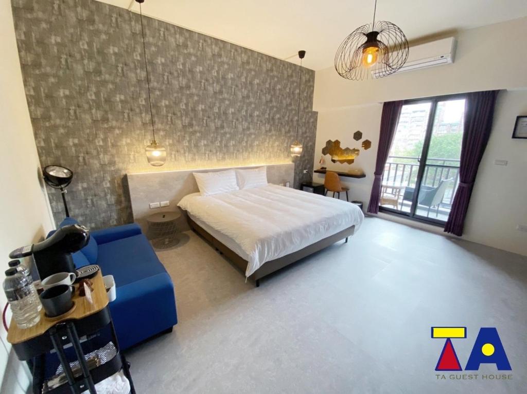 a bedroom with a white bed and a blue couch at Ta 溫泉會館 in Jiaoxi