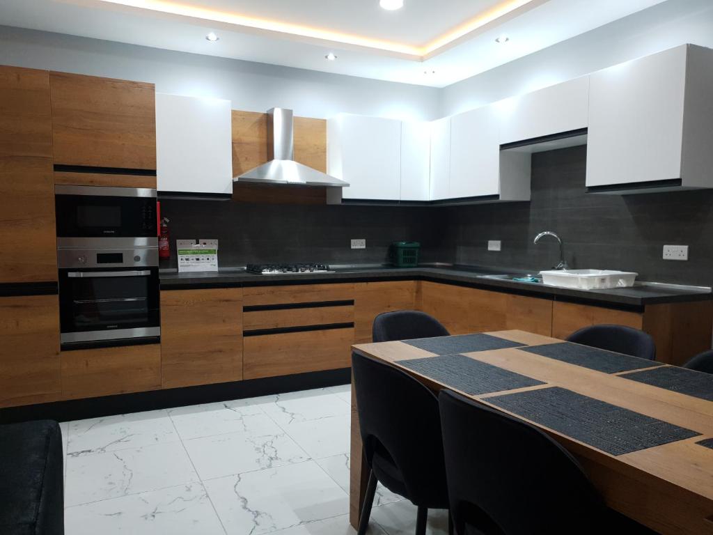 a kitchen with wooden cabinets and a table with chairs at A Ground Floor Maisonette - Mellieha Bay in Is-Sellum