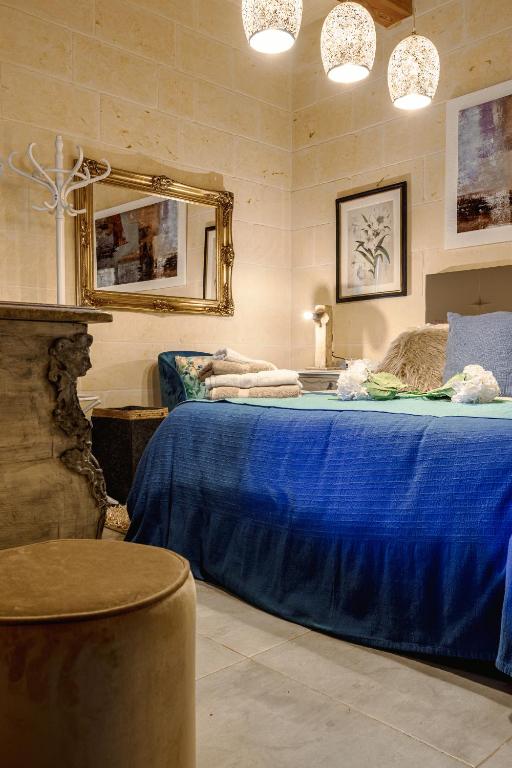 a bedroom with a blue bed and a mirror at Ajuga Luxury Boutique B&B in Qala