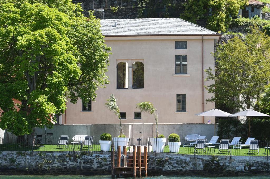 una casa con sedie e ombrelloni di fronte di Bifora65 flats and garden - Lakeview a Orta San Giulio