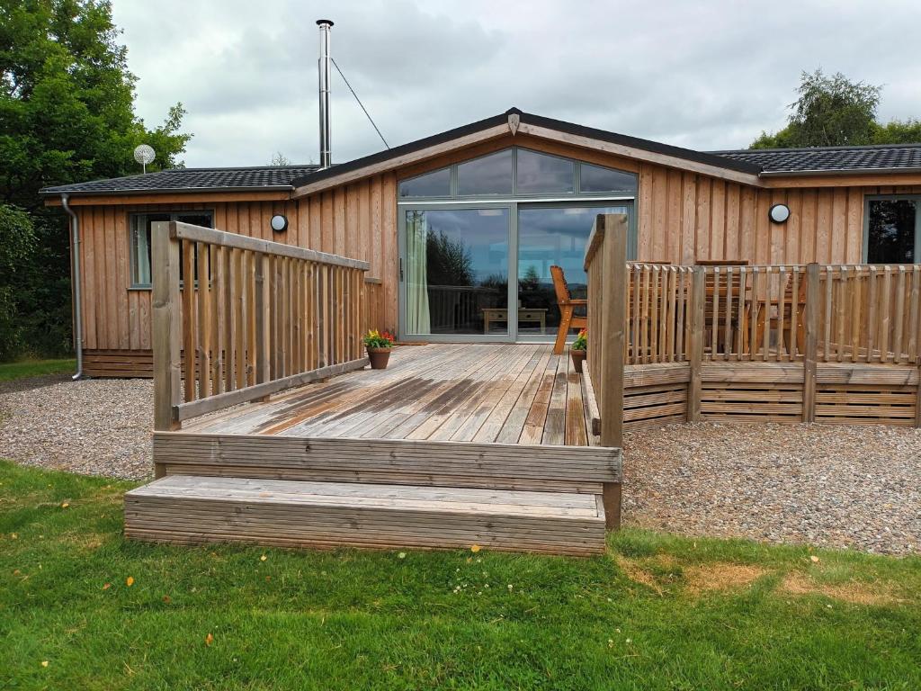 a cabin with a wooden deck with a sliding glass door at Birch Lodge, Pitlandie - Luxury 2 Bedroom Lodge with Sauna in Perth