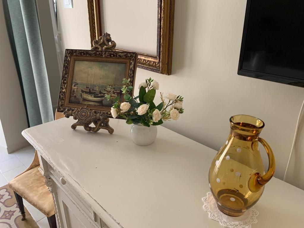 a table with a vase and a picture and a mirror at Dimora del Castellano CASA SATURNO in Gioia del Colle
