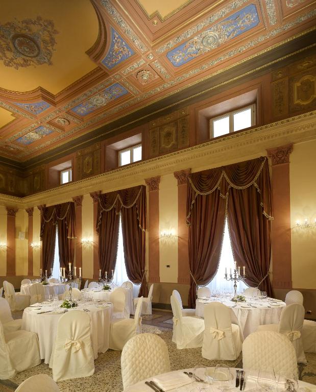 Un salón de banquetes con mesas y sillas blancas. en GH Palazzo Suite & SPA, en Livorno