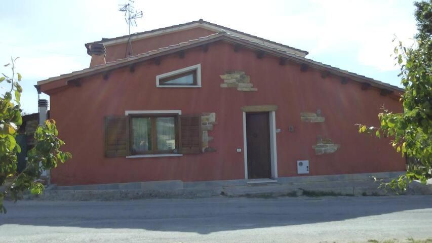 a red building with a door and a window at Rustico Zagara in Buseto Palizzolo