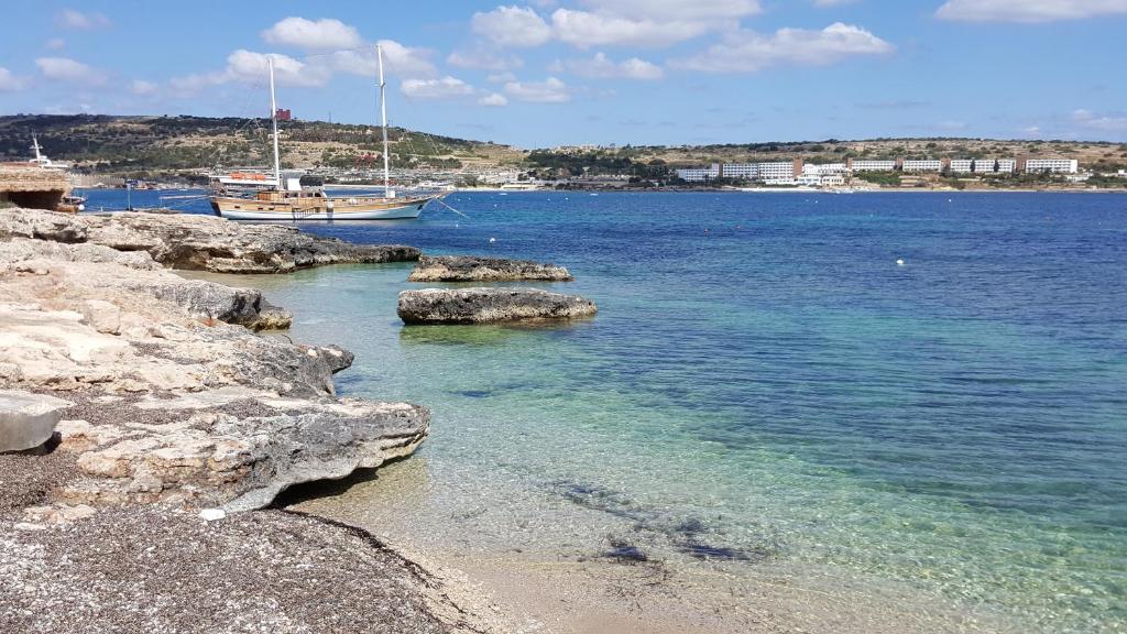 un barco está atracado en una playa cerca del agua en Single room for one person only 5 Minutes walk to Mellieha Bay Beach, en Mellieħa