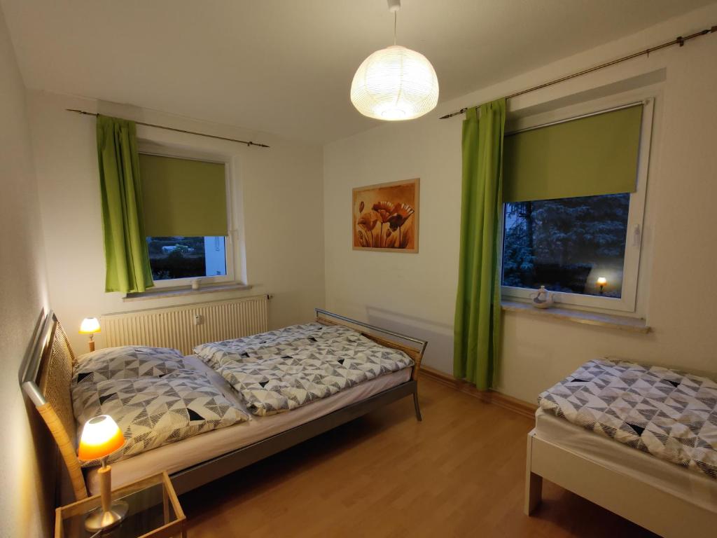 1 Schlafzimmer mit 2 Betten und 2 Fenstern mit grünen Vorhängen in der Unterkunft Green Oelsnitz am Hegebach mit Netflix und Parkplatz Self Check-in in Oelsnitz