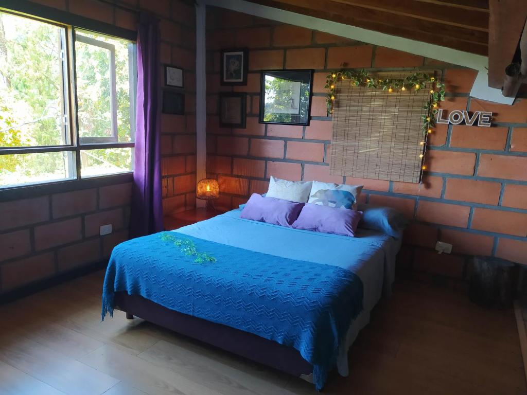 1 dormitorio con 1 cama azul en una pared de ladrillo en Refugio en las Nubes, en Santa Elena