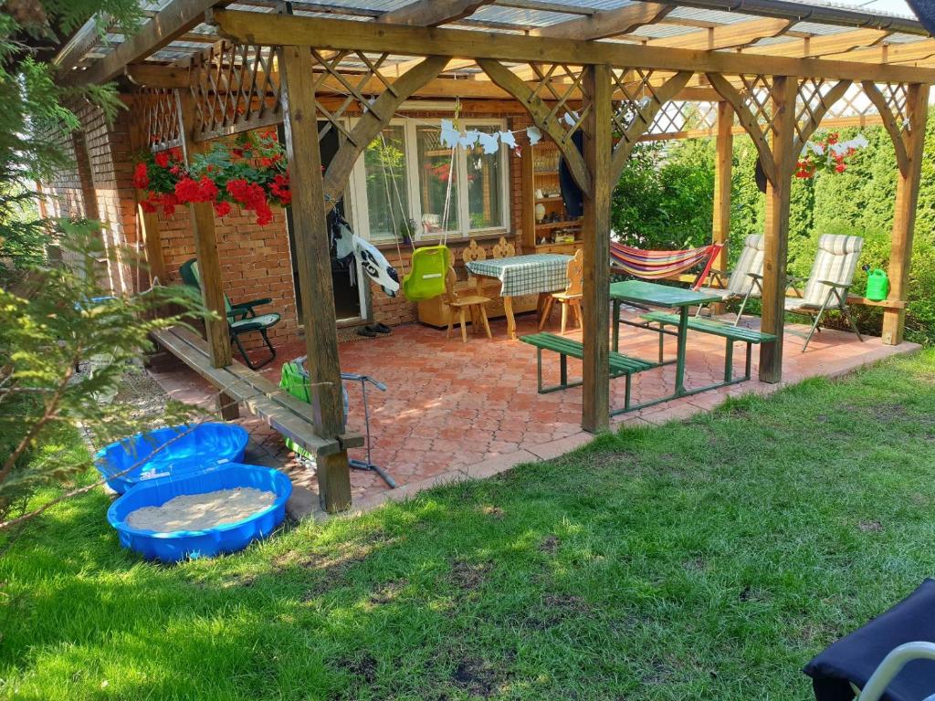 un patio con mesa y sillas bajo una pérgola de madera en A summer house Zarabie Domek letniskowy Zarabie en Myślenice