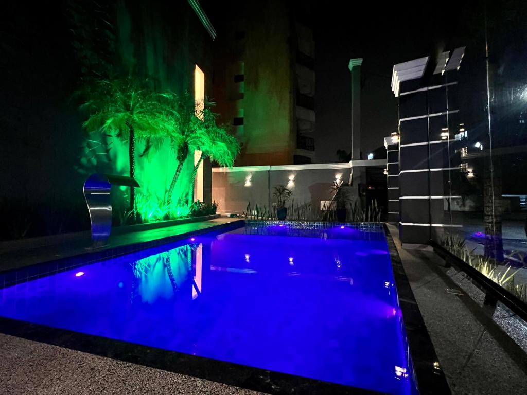 a swimming pool at night with blue lights at Marmeu Tombo com Hidro Aquecida Privativa in Guarujá