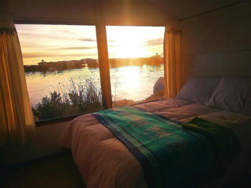 Schlafzimmer mit einem Fenster mit Blick auf das Wasser in der Unterkunft CHUYPAS DEL TITICACA in Puno