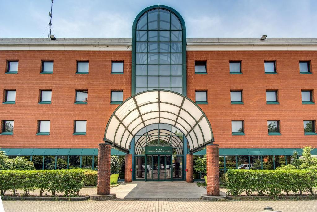 un gran edificio de ladrillo con un arco delante de él en Hotel Della Rotonda, en Saronno