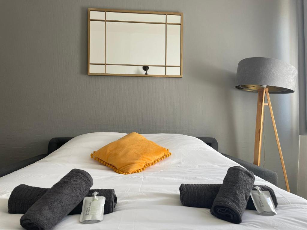białe łóżko z żółtą poduszką i lampą w obiekcie Time Capsule - Studio cosy w mieście Caluire-et-Cuire