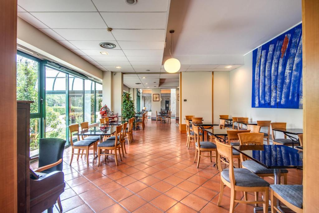 jadalnia ze stołami, krzesłami i oknami w obiekcie Hotel Della Rotonda w mieście Saronno