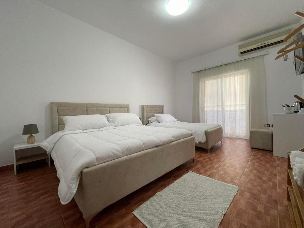 una grande camera bianca con due letti e una finestra di Villa Oasis a Berat