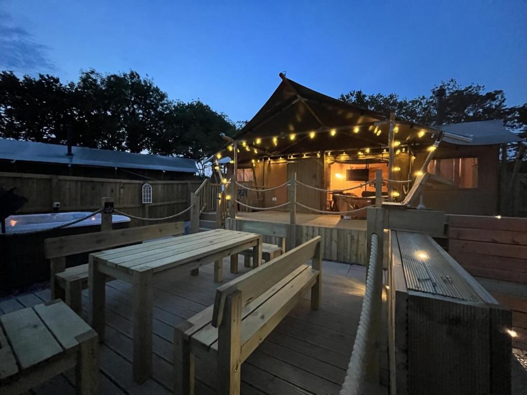 a deck with benches and a gazebo with lights at Lion King Safari Tent in Tenby