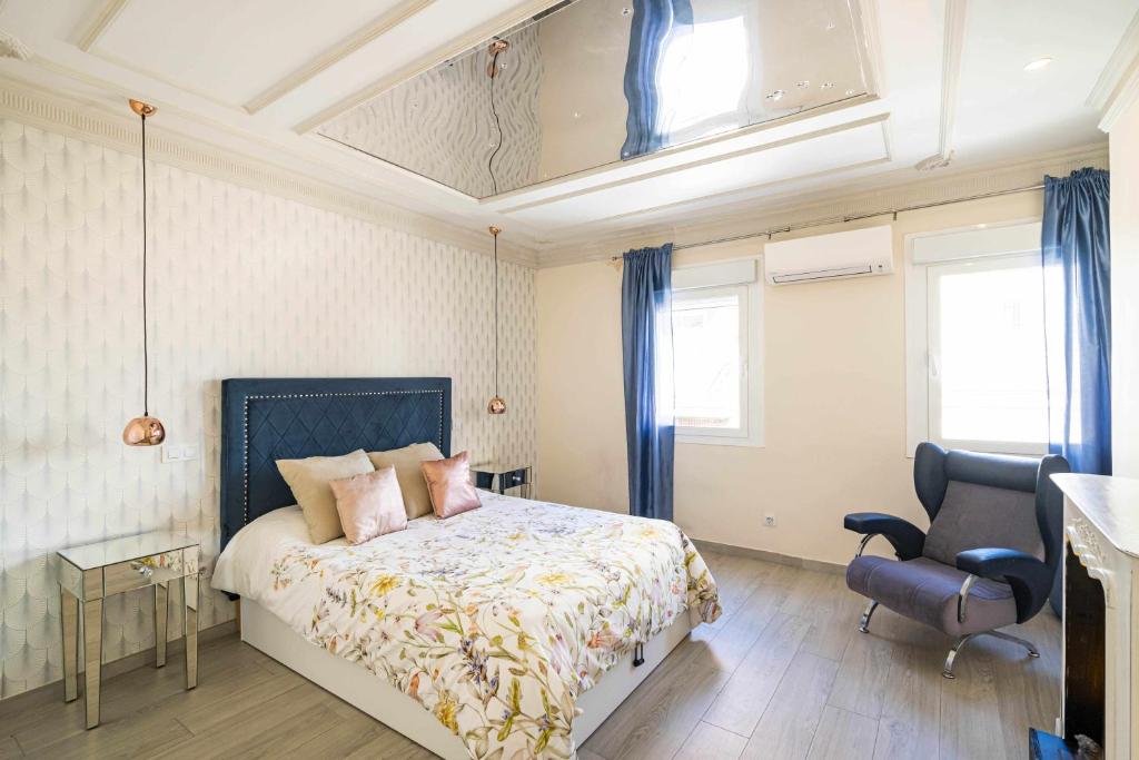 a bedroom with a bed and a chair and windows at Cuidadosamente decorado apartamento junto al metro in Madrid