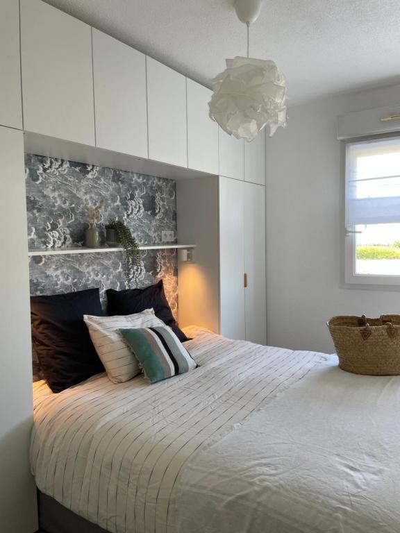 a white bedroom with a large bed with pillows at Capsule Océan, à moins de 10 min de la plage in Aytré