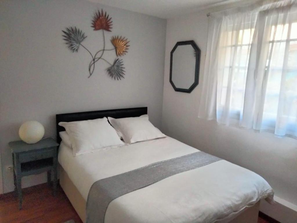1 dormitorio con cama blanca, espejo y ventana en beautiful apartment with garden, en Amélie-les-Bains-Palalda