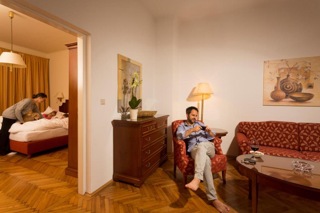un hombre sentado en una silla en una habitación de hotel en City Appartements - Hotel City Central en Viena