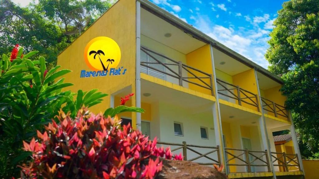 a yellow building with a sign on it at Maresias Flats Unidade I in Maresias
