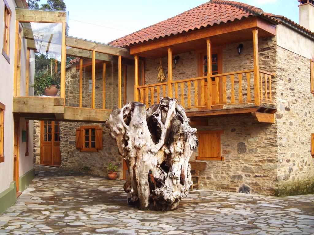 una casa con un tronco de árbol delante de ella en Muiño das Cañotas, en O Lourido