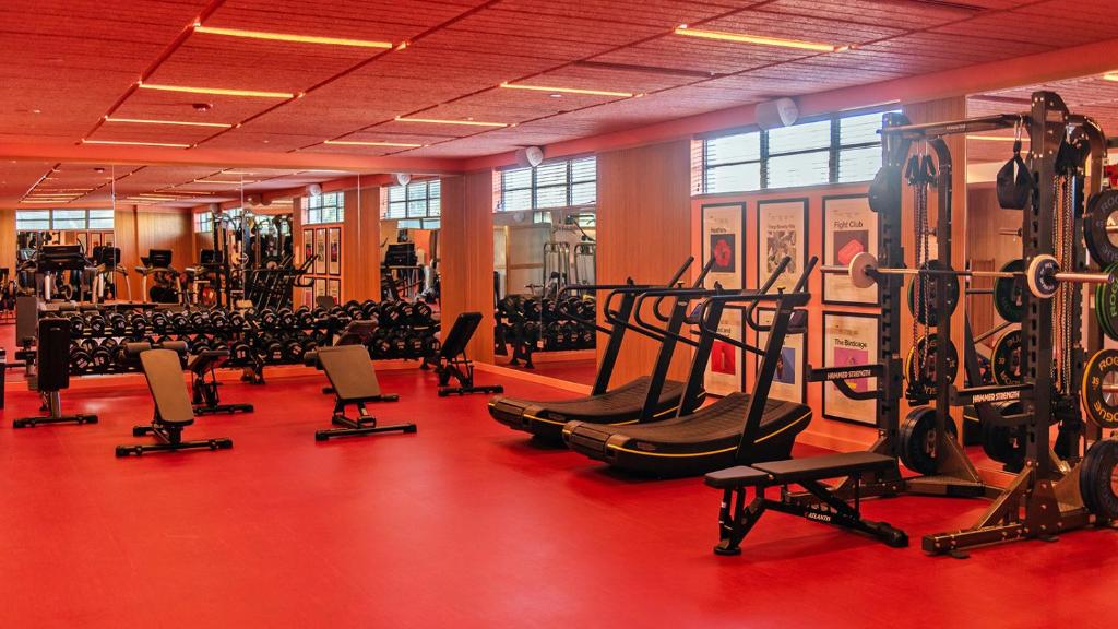 a gym with rows of exercise equipment on a red floor at The Standard Miami in Miami Beach