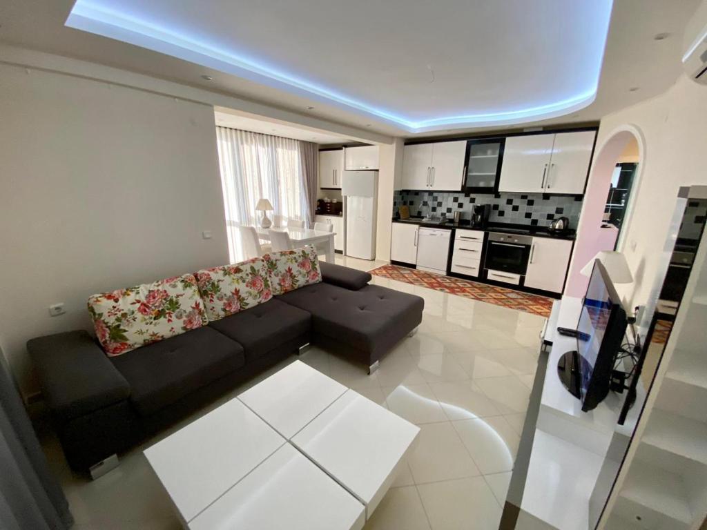 a living room with a black couch and a kitchen at Modern 2bedroom apt on Cleopatra (WiFi,pool) in Alanya