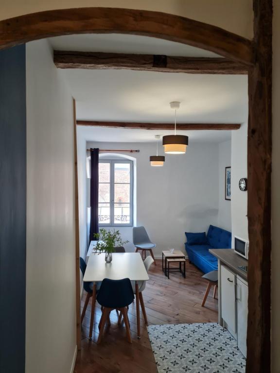 uma sala de estar com uma mesa e um sofá azul em Triplex avec vue sur place du centre historique. em Foix