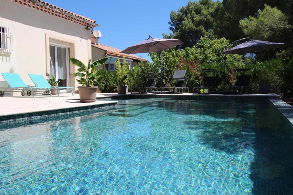 - une piscine avec des chaises et des parasols à côté d'une maison dans l'établissement Au cœur de la Roque d'Anthéron - Aux portes du Lubéron, à La Roque-dʼAnthéron