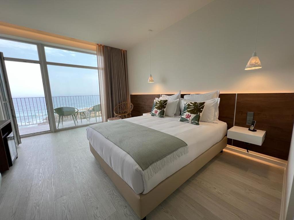 a bedroom with a large bed with a view of the ocean at Porto Covo Praia Hotel & SPA in Porto Covo