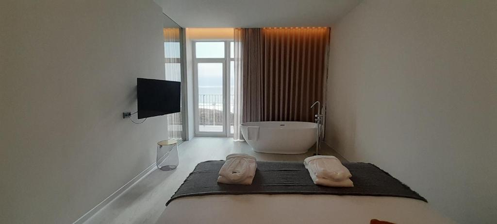 a white bathroom with a tub and a television at Porto Covo Praia Hotel & SPA in Porto Covo