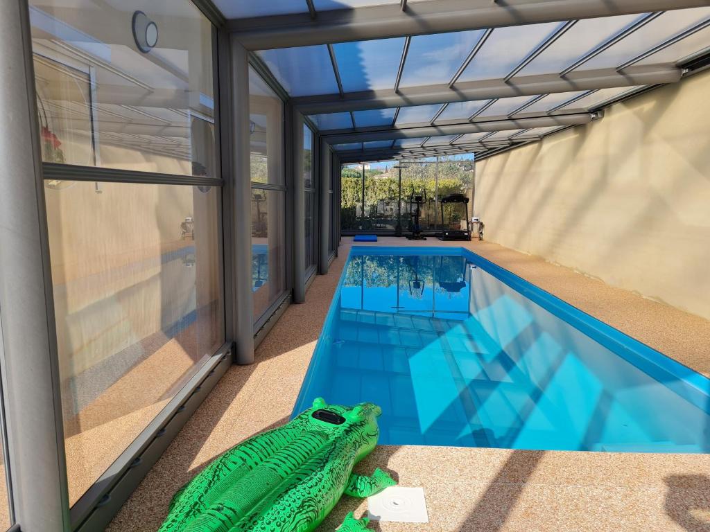 een zwembad met een schildpaddenspeeltje naast een huis bij Chambres d'hôtes B&B La Bergeronnette avec piscine couverte chauffée in Bizanet