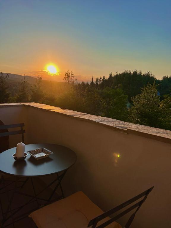 a table on a balcony with a sunset in the background at Villa Kastro Elassona in Elassona