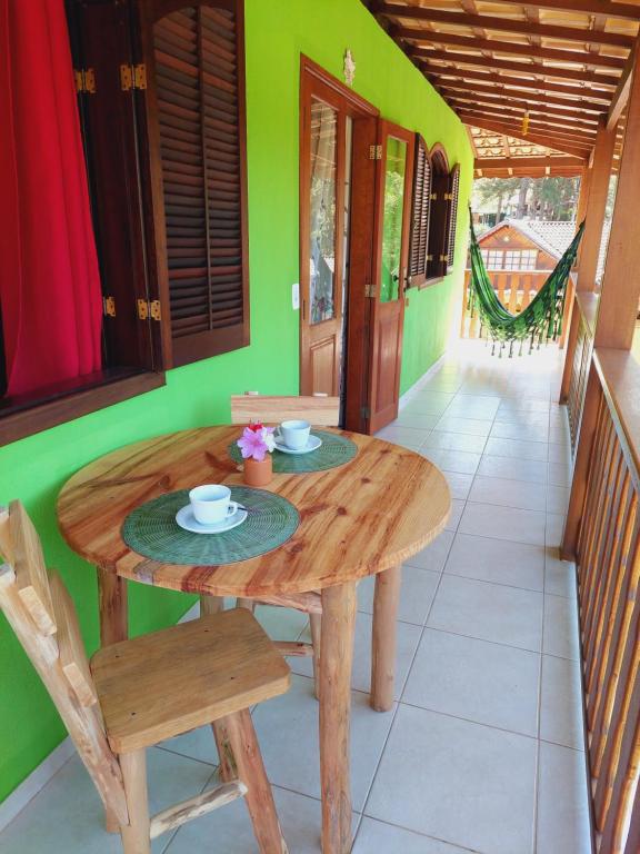 a wooden table and chairs on the porch of a house at Casa Canto Verde in Visconde De Maua