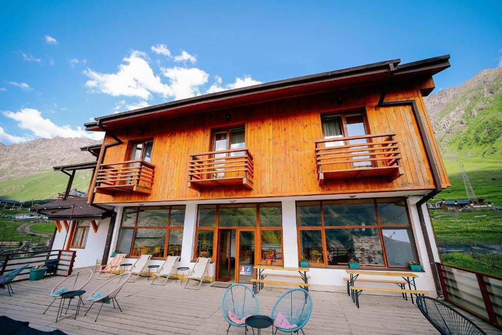 Alpenhaus Kazbegi Hotel & Restaurant في كازباجي: مبنى به كراسي وطاولات على فناء